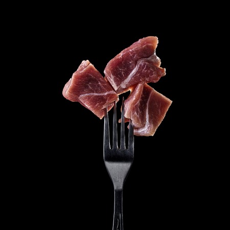 Fresh and raw meat on a fork on black background.の写真素材