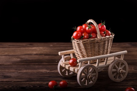 Red tomatoes in wicker basket on the wooden table. Vegetables harvest. Organic fresh harvested vegetablesの写真素材