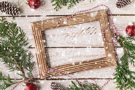 Christmas decoration on the white wooden background. Christmas interior with photo frame, decorative branches, presents on wooden table. New Year winter composition. Top View. Space for text