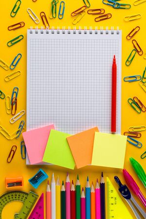 Creative flat lay back to school concept with Notepad on bright yellow paper background with copy space, template for text or design. colorful School stationery on colorful backgroundの写真素材