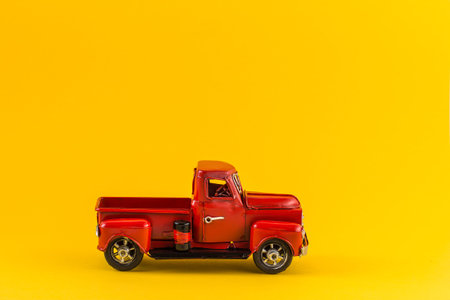Red toy truck on bright yellow backgroundの写真素材