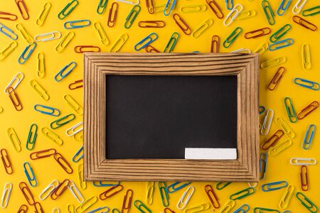 Paper clips and empty photo frame on yellow paper background.の写真素材