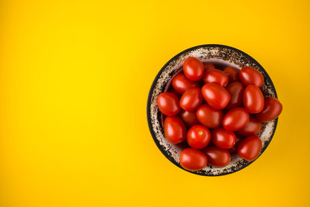 Flat lay with red tomatoes on yellow background. tomatoes in a metal plate on bright yellow paper background. Minimalism fashion styleの写真素材