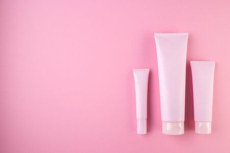 Collection of three cosmetic tubes on pastel pink background. Plastic tube with face or body cream on pink  with copy space. Top view, flat lay.の写真素材