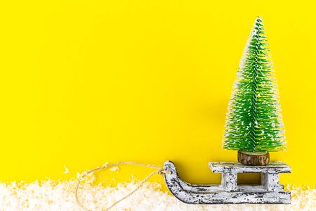 Christmas tree and vintage wooden sled over trendy background with snow. Merry Christmas and Happy New Year greeting card. Minimal winter background. Flat lay copy spaceの写真素材