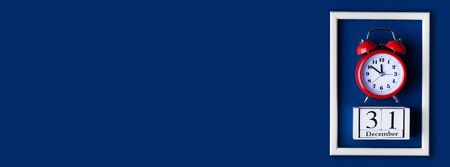 Christmas composition. White photo frame with alarm clock on a blue classic background. Christmas, New Year concept. Flat lay copy space. Trend color of 2020 year. Template mockup long wide bannerの写真素材