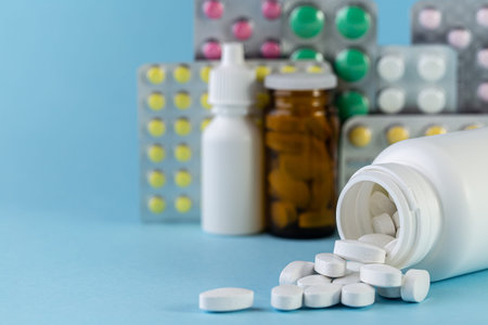 Pills spilling out of white bottle on blue background. with copy space. Pharmaceutical medicament,...