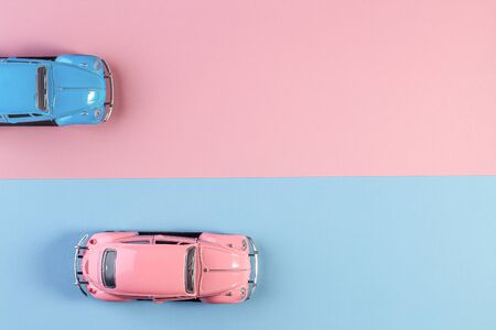 Small vintage retro toy cars on a pink and blue background. Racing cars on the race track. concept for competition or childhood. winner and loser concept.の写真素材