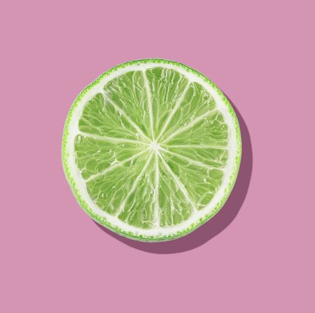Green lime slices on vibrant pink color background. Minimal summer concept. flat lay food textureの写真素材