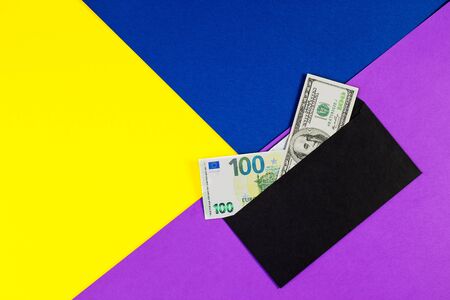 Euro and American dollar banknotes in black envelope on color paper background. Gift envelope with money as bonus, reward, benefits concept, bribe gift. Shadow economy, illegal salary without taxes.の写真素材