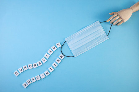 Wooden hand with the words quarantine and coronavirus written on a blue background. Pandemic Covid-19 Coronavirus quarantine conceptの写真素材