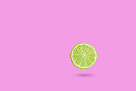 Green lime slic on vibrant pink color background. Minimal summer concept.の写真素材