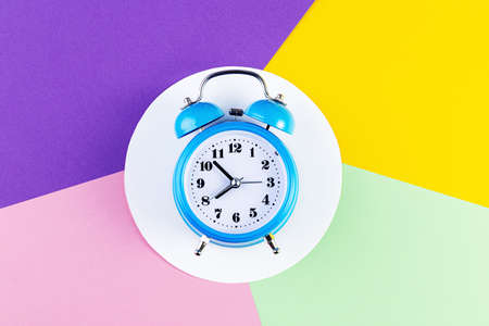 Blue vintage alarm clock on a colorful paper background.の写真素材
