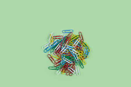 Bunch of colorful paper clips on green background. Creative flat lay back to school concept with...