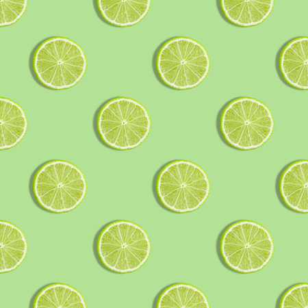 Colorful fruit seamless pattern of fresh lime slices on green background. Trendy sunlight Summer...