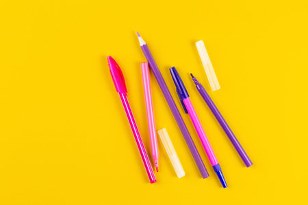 Set of colored pens on yellow paper background with copy space. Flat lay, Top view. template for...