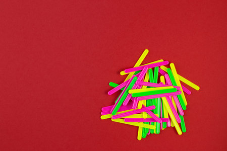 Counting sticks of different colors for classes with children on red paper background with copy...