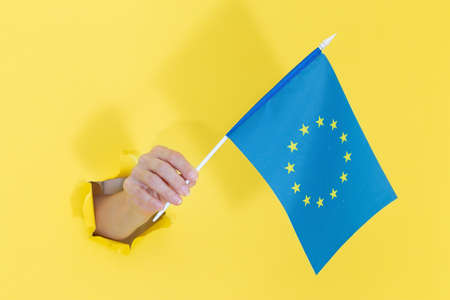 Hand holding american flag from yellow torn paperの写真素材