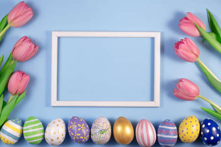 Tulips flowers and Easter eggs with wooden frame on blue background. Card for Happy Easterの写真素材