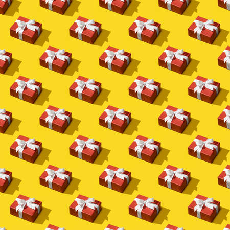 Seamless pattern made of red gift boxes tied with white ribbons on yellow background. Creative Christmas pattern from Gift box. Christmas isometric pattern. Holiday concept, congratulationsの写真素材