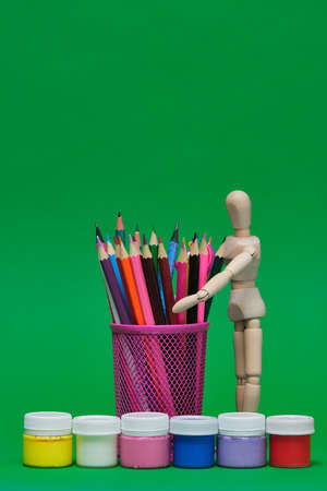 Back to school Education concept. Painting supplies, colorful pencils and plastic jars with paint of different colors for childrens creativity on green background. Materials for drawing, creativityの写真素材