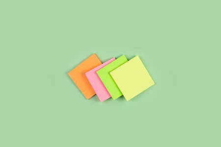 Colorful sticky notes on green background. four colored notes on an isolated green background. Stack empty sticky post note paper sheetの写真素材