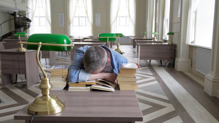 Portrait of caucasian Senior man working with book in public library. Adult student at the library,...