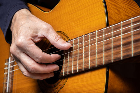 Guitarist playing acoustic guitar on black background, selective focus. A male musician plays the guitar. cover for online courses. A man playing acoustic guitar. musical concept copy spaceの写真素材