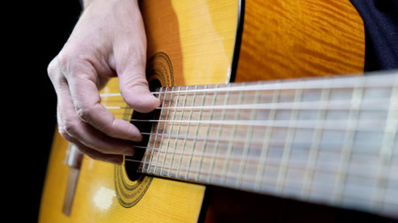 Guitarist playing acoustic guitar on black background, selective focus. A male musician plays the guitar. cover for online courses. A man playing acoustic guitar. musical concept copy spaceの写真素材