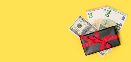black gift box with a cash money on a yellow background. Festive background. Concept of presents, festive and holiday shopping. Holiday backgroundの写真素材