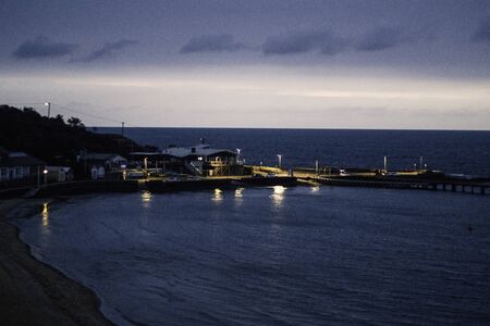 Beach pier at night lit up by the lamps and building lightsの写真素材