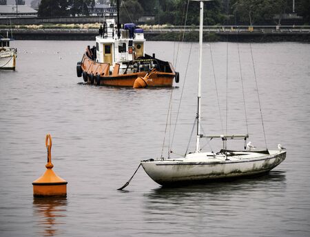 A large and small boat with seagulls on a lake next to an orange buoyの写真素材