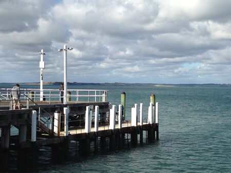 People on an old beach pier with grey clouds overheadの写真素材