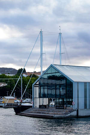 Large cafe building on the edge of a pier with buildings, mountains and clouds in the backgroundのeditorial素材