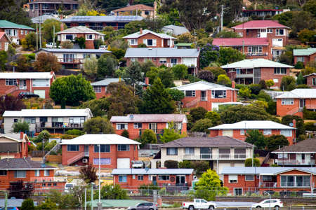 A pattern of residential brick houses on a hill with foliage