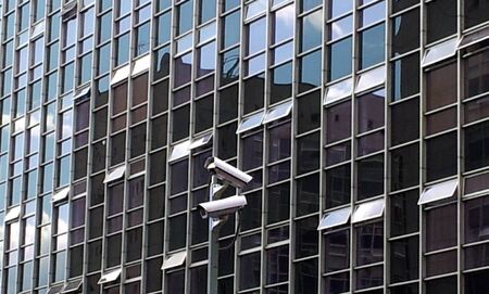 Surveillance cameras. View of a glass facade of a office building where the sky is reflected.の写真素材