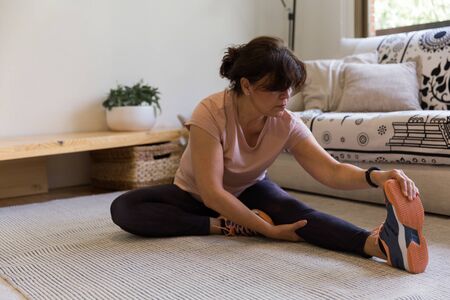 Scene of a woman in the living room at home. She is doing stretching exercises.の写真素材