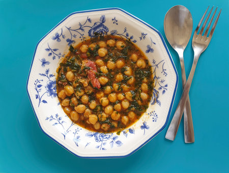 Close up photo of chickpea stew with spinach in a dish with blue backgroundの写真素材