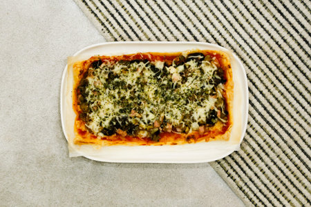 White plate with square Pizza on triangular black and white lines as background.