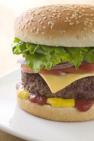 Cropped hamburger with cheese, lettuce and tomato on sesame bun.の写真素材