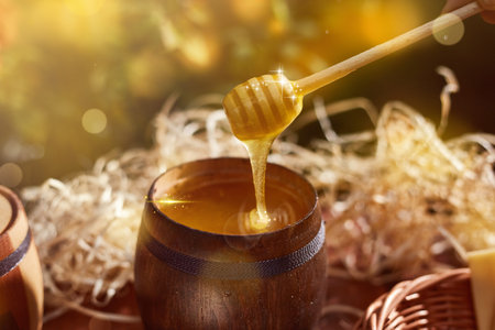 a jar of sweet honey in a bucket on a wooden table in the garden with flowers for breakfast delicious food. High quality photoの写真素材