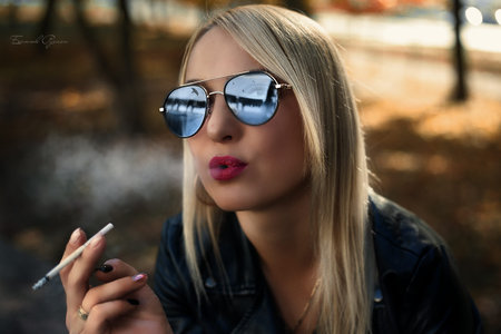 Fashion art portrait of beauty model woman in bright lights with colorful smoke. Smoking girl, Close up of a female inhaling from an electronic cigarette. High quality photoの写真素材