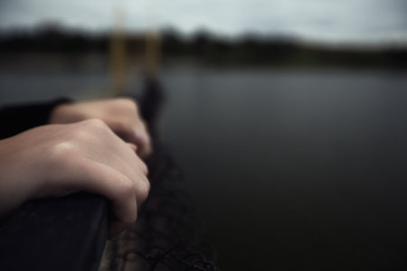 bullying teen girl aloofness young detachment a lonely helpless woman thinks about life and does not want to live looks at a gloomy photo into the distance and a renunciate thinks alone with herself and is bored upset on a pier by the water sits on a pier in the evening. High quality photoの写真素材