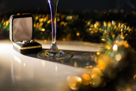 A glass on the table among the New Year's decorations. Box with earrings. Jewelry. Holiday gift. Background.の写真素材