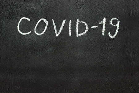 COVID-19 is written in white chalk on a chalk board.の写真素材