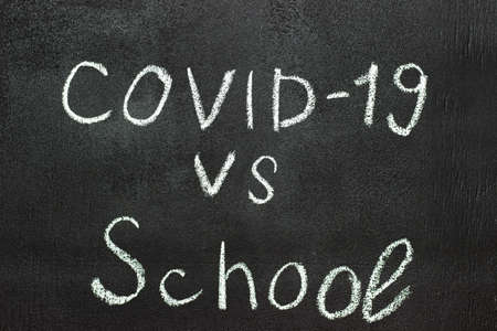 COVID-19 against school is written on a blackboard in white chalk.の写真素材