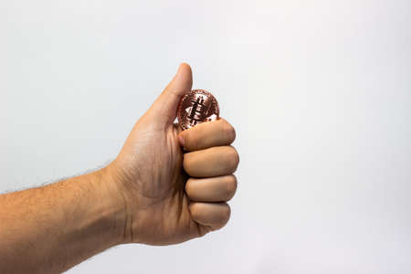 Hand holds physical bitcoin coin. Bitcoin in hand on white background. Bitcoin cryptocurrency on white canvasの写真素材