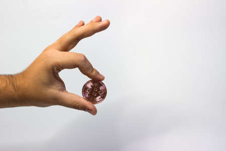 Hand holds physical bitcoin coin. Bitcoin in hand on white background. Bitcoin cryptocurrency on white canvasの写真素材