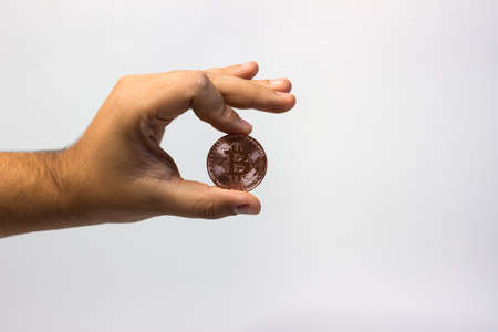 Hand holds physical bitcoin coin. Bitcoin in hand on white background. Bitcoin cryptocurrency on white canvasの写真素材