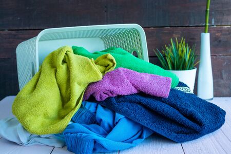 Basket with dirty Laundry on a white wooden background. House cleaning. Dirty Laundry falls out of the basket.の写真素材